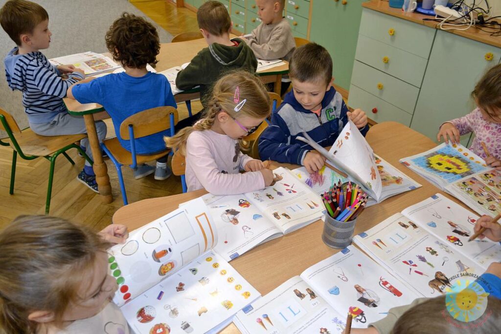 Siedzące dzieci przy przedszkolnym stoliku, wykonują pracę - Przedszkole Samorządowe Nr 2 Pod Słonkiem w Białymstoku