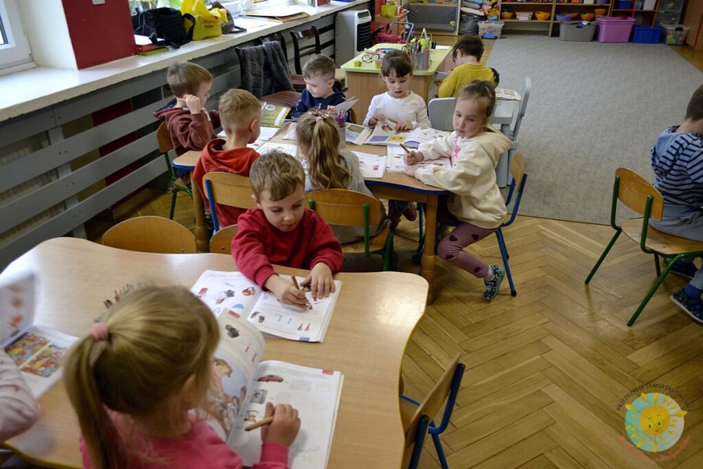 Siedzące dzieci przy przedszkolnym stoliku, wykonują pracę - Przedszkole Samorządowe Nr 2 Pod Słonkiem w Białymstoku