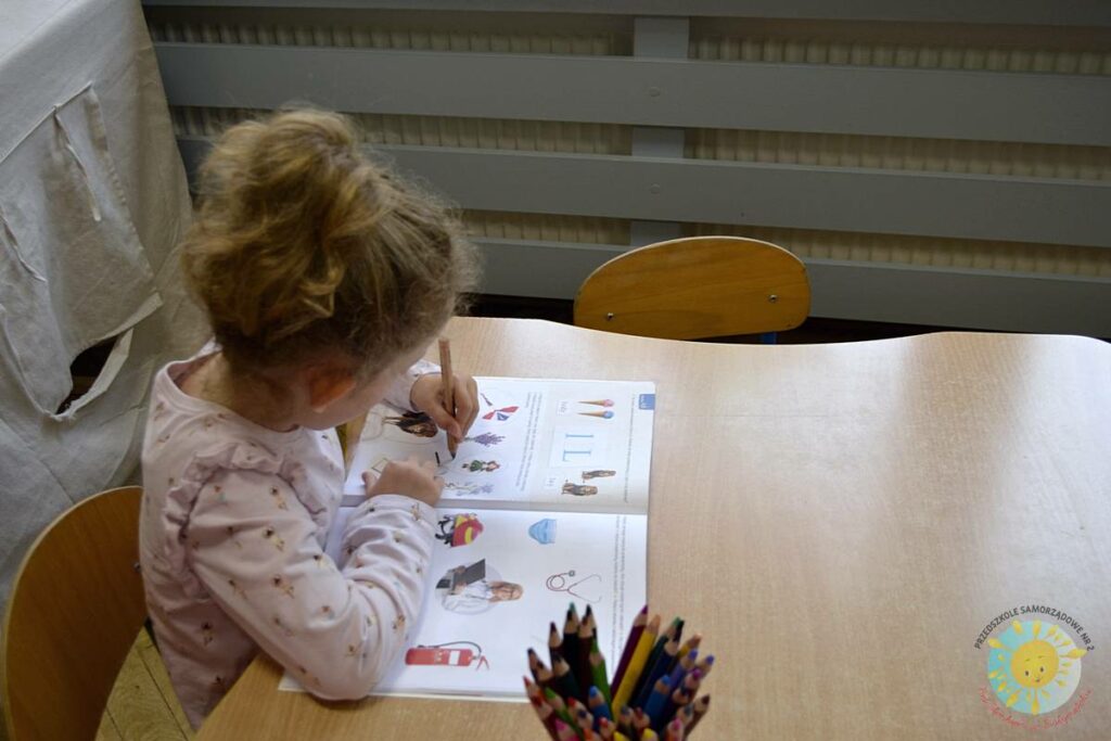 Siedzące dzieci przy przedszkolnym stoliku, wykonują pracę - Przedszkole Samorządowe Nr 2 Pod Słonkiem w Białymstoku