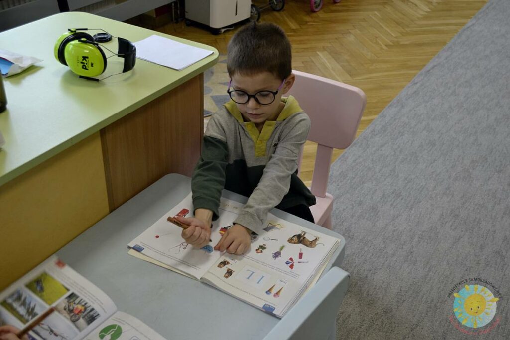 Siedzące dzieci przy przedszkolnym stoliku, wykonują pracę - Przedszkole Samorządowe Nr 2 Pod Słonkiem w Białymstoku