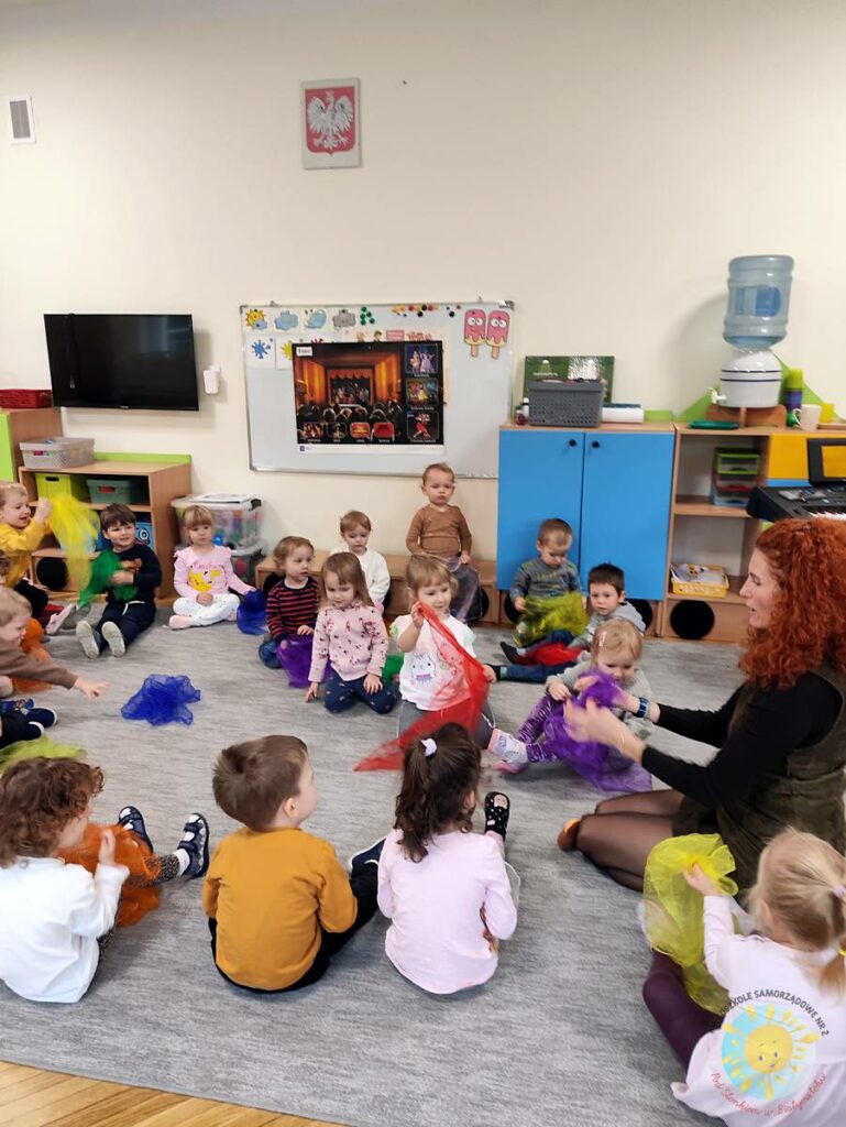 Siedzące dzieci na dywanie, które biorą udział w zajęciach - Przedszkole Samorządowe Nr 2 Pod Słonkiem w Białymstoku