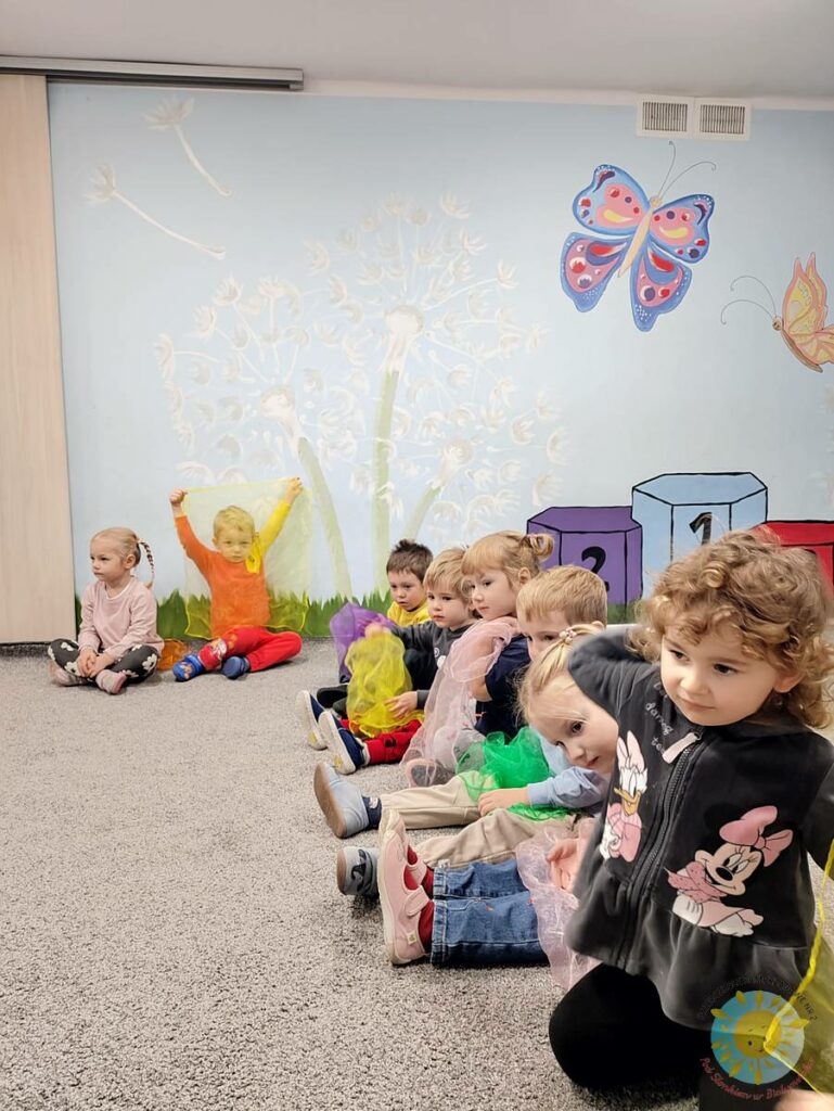 Siedzące dzieci na dywanie, które biorą udział w zajęciach - Przedszkole Samorządowe Nr 2 Pod Słonkiem w Białymstoku