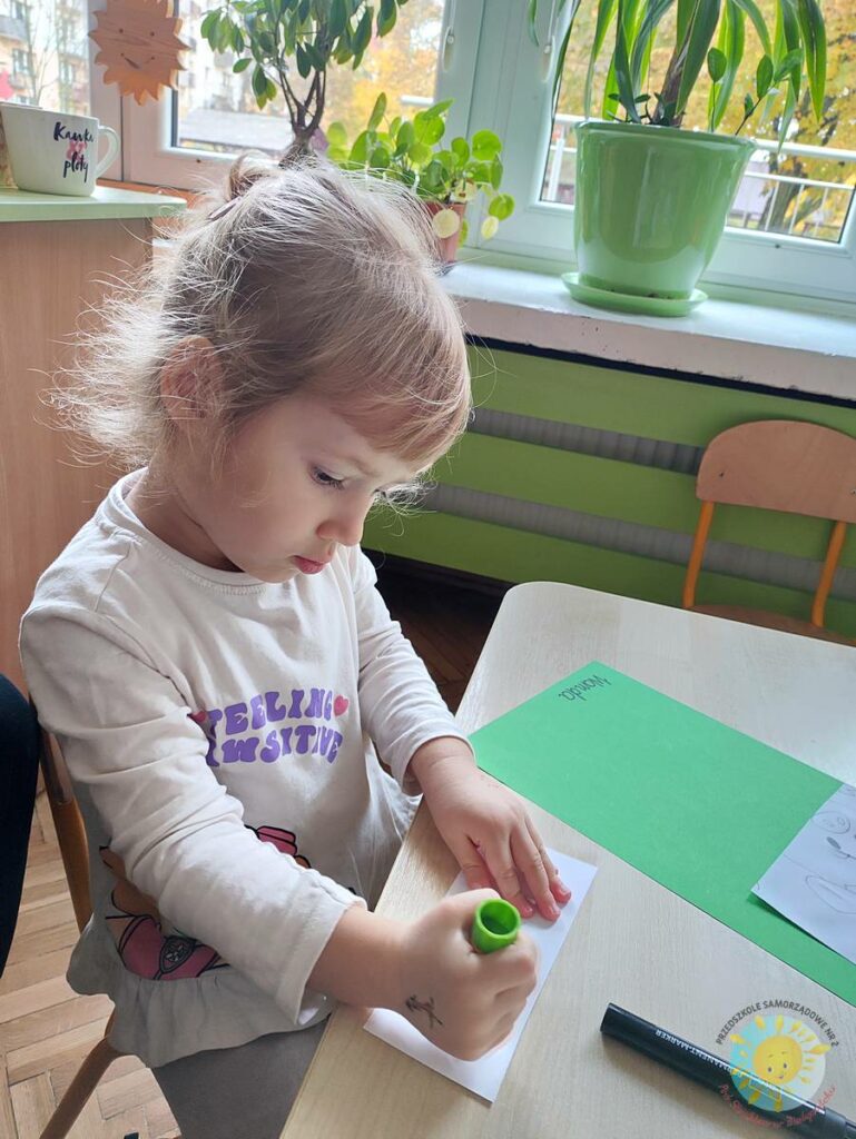 Siedzące dzieci przy przedszkolnym stoliku, wykonują pracę - Przedszkole Samorządowe Nr 2 Pod Słonkiem w Białymstoku