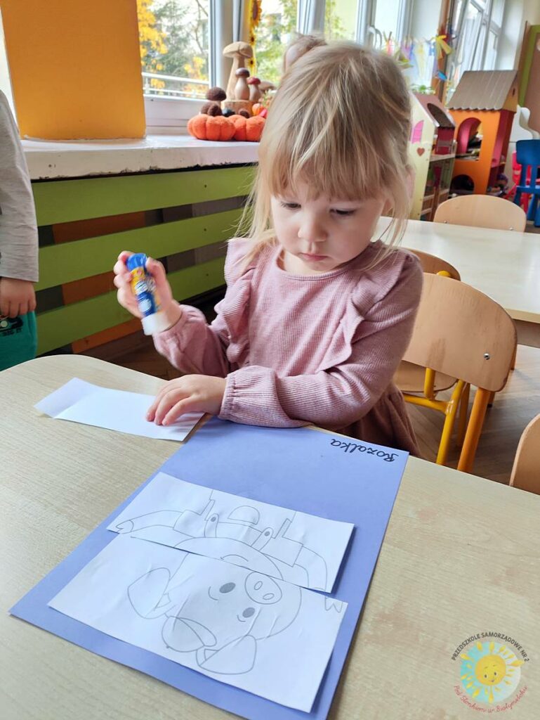 Siedzące dzieci przy przedszkolnym stoliku, wykonują pracę - Przedszkole Samorządowe Nr 2 Pod Słonkiem w Białymstoku