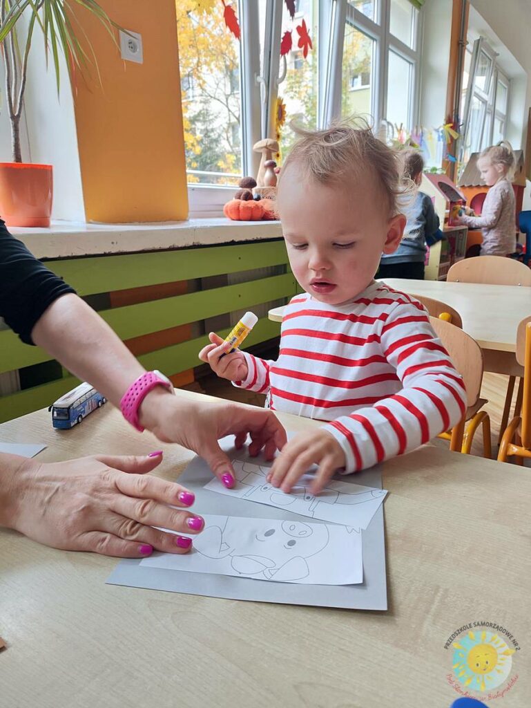 Siedzące dzieci przy przedszkolnym stoliku, wykonują pracę - Przedszkole Samorządowe Nr 2 Pod Słonkiem w Białymstoku