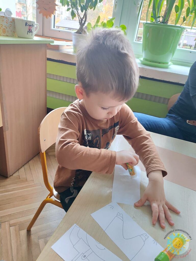 Siedzące dzieci przy przedszkolnym stoliku, wykonują pracę - Przedszkole Samorządowe Nr 2 Pod Słonkiem w Białymstoku