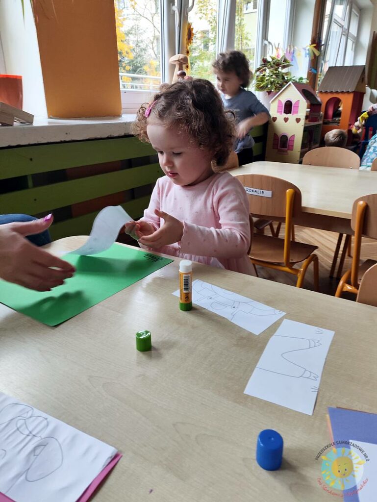 Siedzące dzieci przy przedszkolnym stoliku, wykonują pracę - Przedszkole Samorządowe Nr 2 Pod Słonkiem w Białymstoku