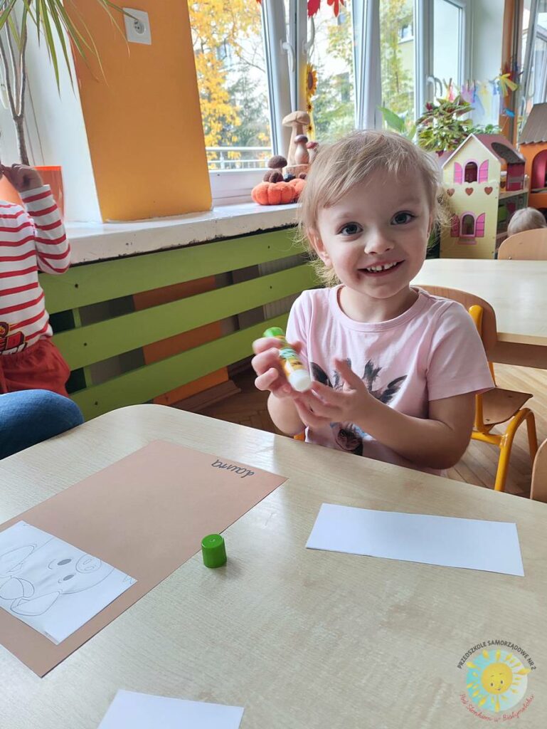 Siedzące dzieci przy przedszkolnym stoliku, wykonują pracę - Przedszkole Samorządowe Nr 2 Pod Słonkiem w Białymstoku