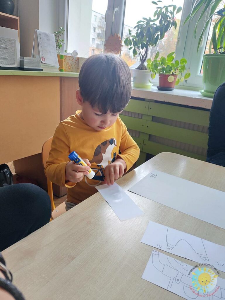 Siedzące dzieci przy przedszkolnym stoliku, wykonują pracę - Przedszkole Samorządowe Nr 2 Pod Słonkiem w Białymstoku