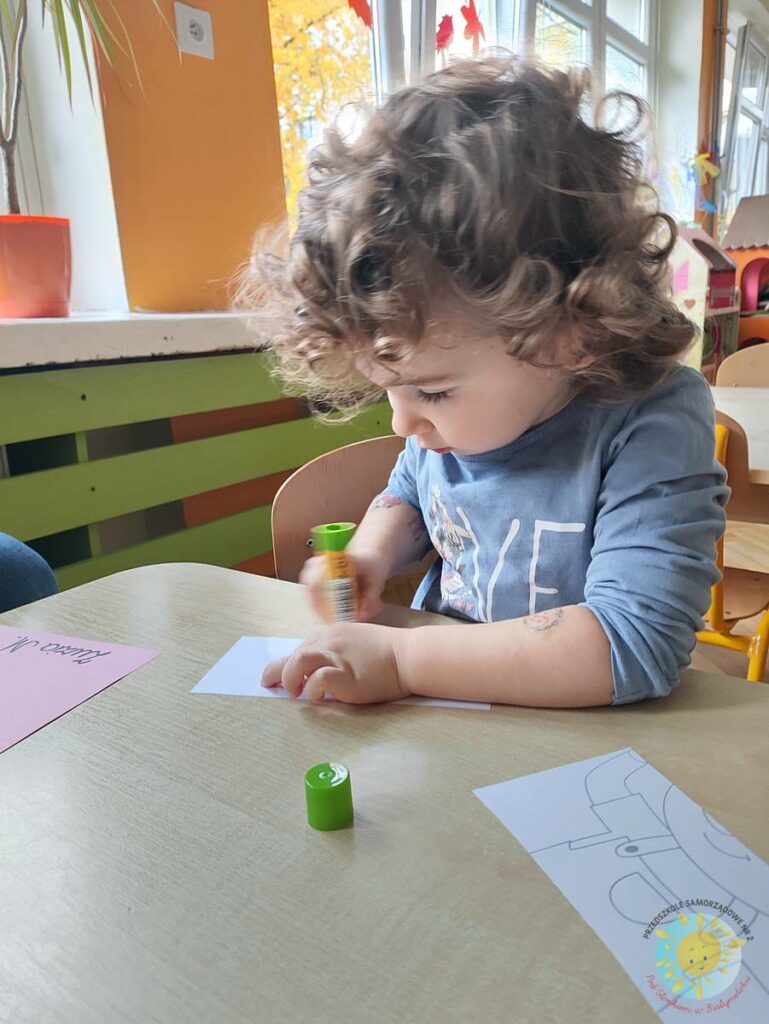 Siedzące dzieci przy przedszkolnym stoliku, wykonują pracę - Przedszkole Samorządowe Nr 2 Pod Słonkiem w Białymstoku