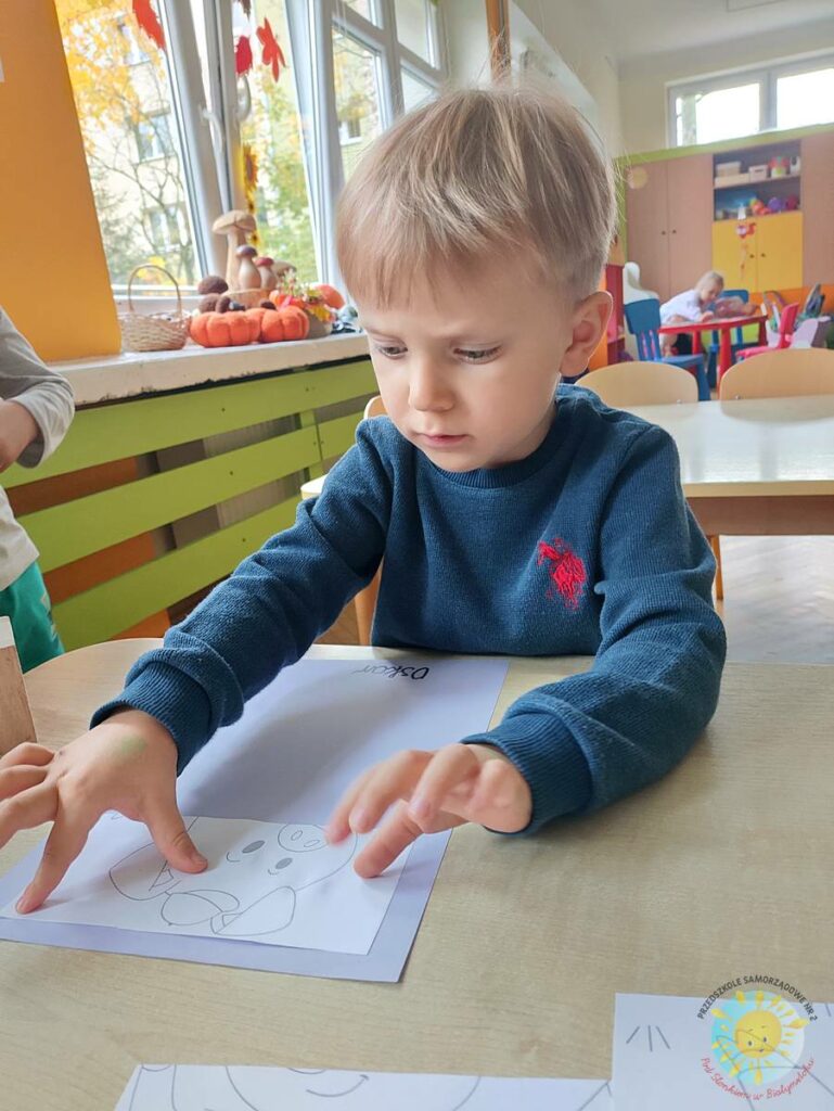 Siedzące dzieci przy przedszkolnym stoliku, wykonują pracę - Przedszkole Samorządowe Nr 2 Pod Słonkiem w Białymstoku