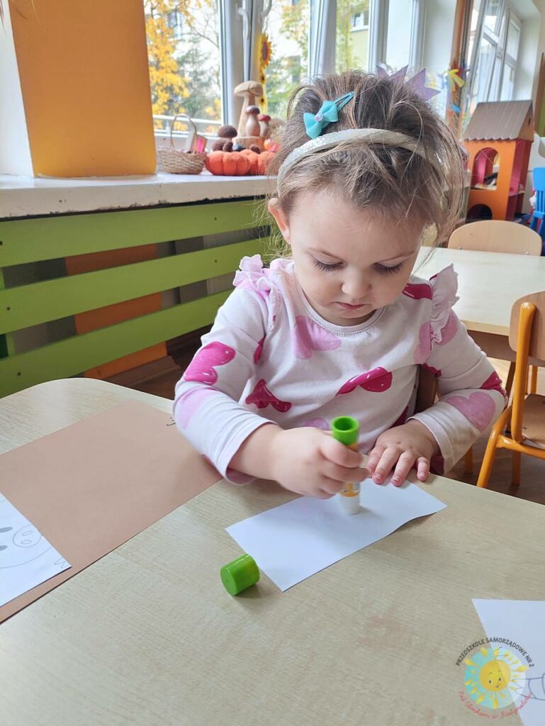 Siedzące dzieci przy przedszkolnym stoliku, wykonują pracę - Przedszkole Samorządowe Nr 2 Pod Słonkiem w Białymstoku