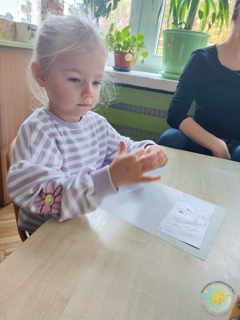 Siedzące dzieci przy przedszkolnym stoliku, wykonują pracę - Przedszkole Samorządowe Nr 2 Pod Słonkiem w Białymstoku