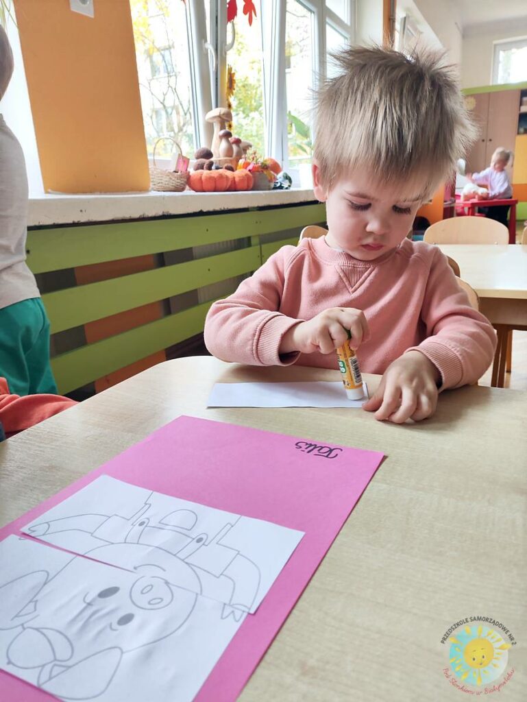 Siedzące dzieci przy przedszkolnym stoliku, wykonują pracę - Przedszkole Samorządowe Nr 2 Pod Słonkiem w Białymstoku