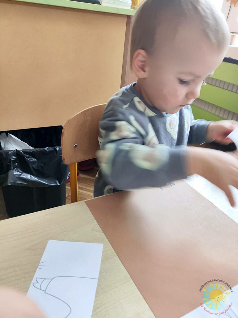 Siedzące dzieci przy przedszkolnym stoliku, wykonują pracę - Przedszkole Samorządowe Nr 2 Pod Słonkiem w Białymstoku