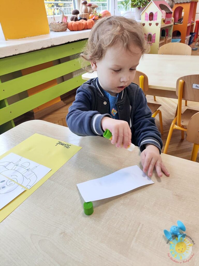 Siedzące dzieci przy przedszkolnym stoliku, wykonują pracę - Przedszkole Samorządowe Nr 2 Pod Słonkiem w Białymstoku