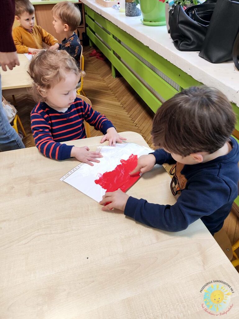 Siedzące dzieci przy stole i wykonują pracę plastyczną - Przedszkole Samorządowe Nr 2 Pod Słonkiem w Białymstoku