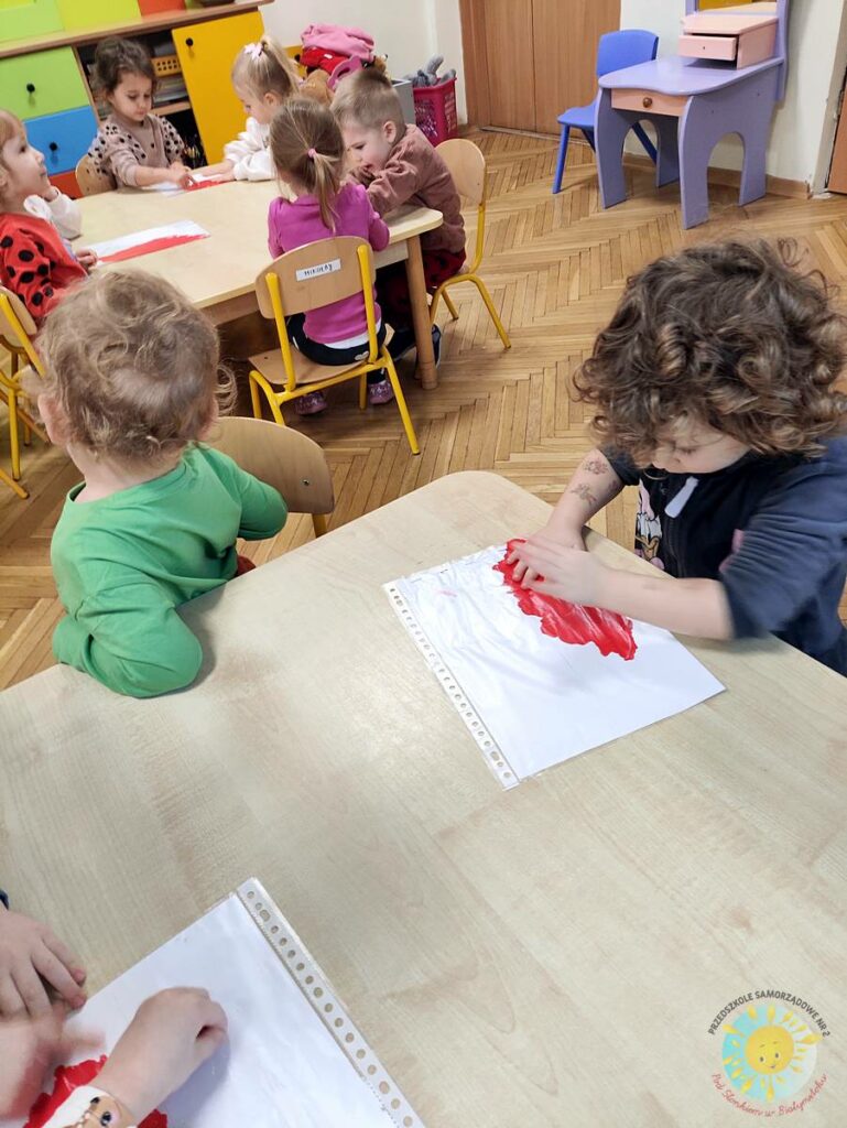 Siedzące dzieci przy stole i wykonują pracę plastyczną - Przedszkole Samorządowe Nr 2 Pod Słonkiem w Białymstoku