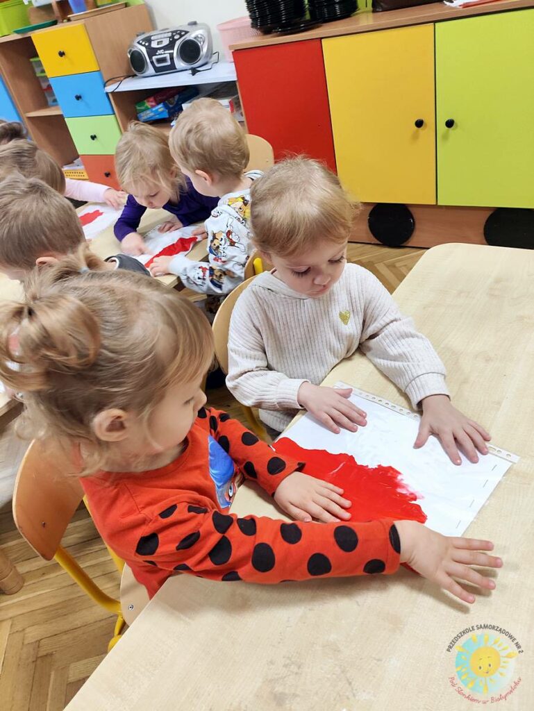 Siedzące dzieci przy stole i wykonują pracę plastyczną - Przedszkole Samorządowe Nr 2 Pod Słonkiem w Białymstoku