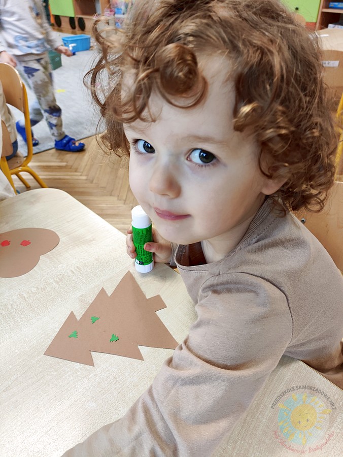 Siedzące dzieci przy stole i wykonują pracę plastyczną - Przedszkole Samorządowe Nr 2 Pod Słonkiem w Białymstoku