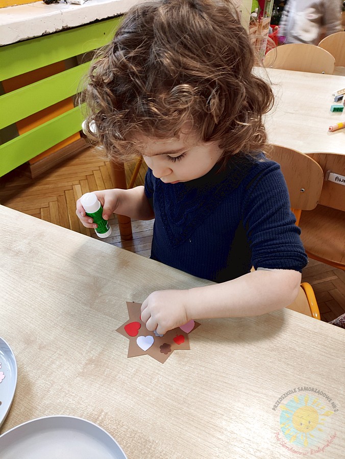 Siedzące dzieci przy stole i wykonują pracę plastyczną - Przedszkole Samorządowe Nr 2 Pod Słonkiem w Białymstoku