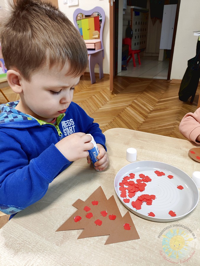 Siedzące dzieci przy stole i wykonują pracę plastyczną - Przedszkole Samorządowe Nr 2 Pod Słonkiem w Białymstoku