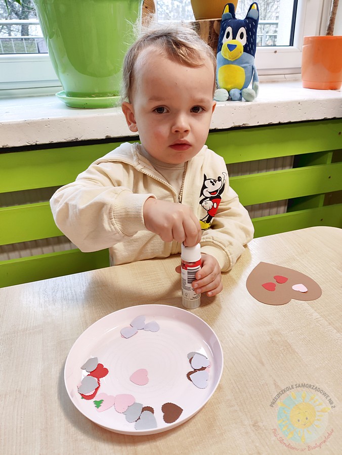 Siedzące dzieci przy stole i wykonują pracę plastyczną - Przedszkole Samorządowe Nr 2 Pod Słonkiem w Białymstoku