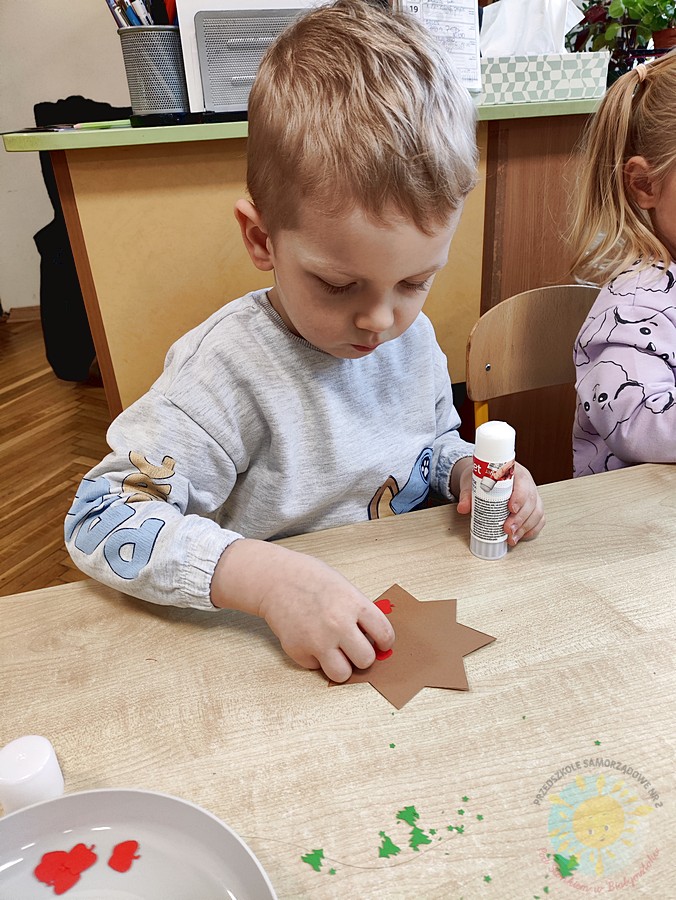 Siedzące dzieci przy stole i wykonują pracę plastyczną - Przedszkole Samorządowe Nr 2 Pod Słonkiem w Białymstoku