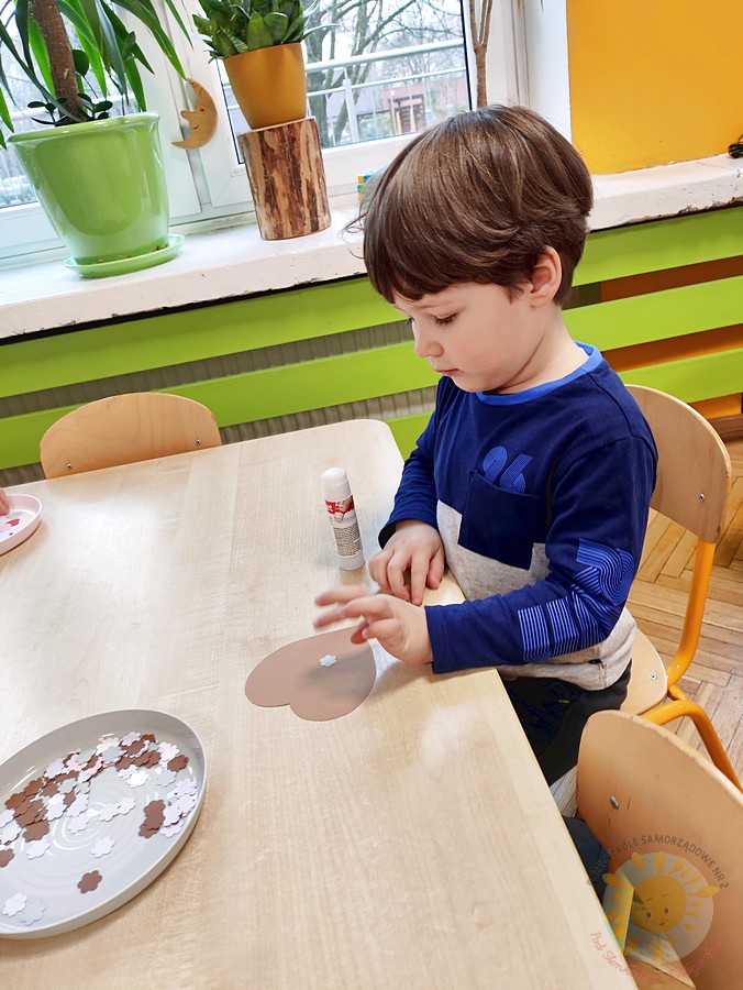 Siedzące dzieci przy stole i wykonują pracę plastyczną - Przedszkole Samorządowe Nr 2 Pod Słonkiem w Białymstoku