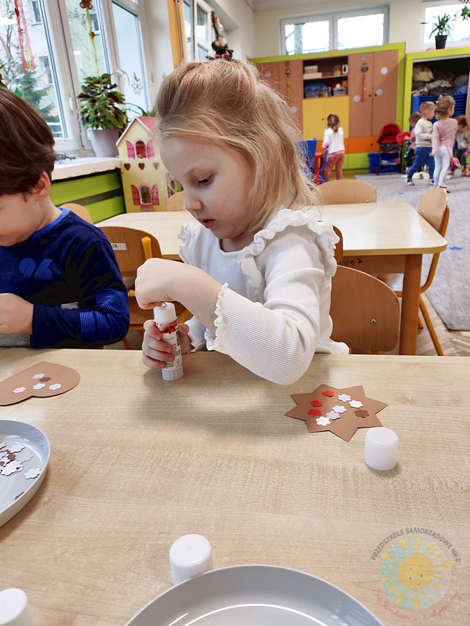 Siedzące dzieci przy stole i wykonują pracę plastyczną - Przedszkole Samorządowe Nr 2 Pod Słonkiem w Białymstoku