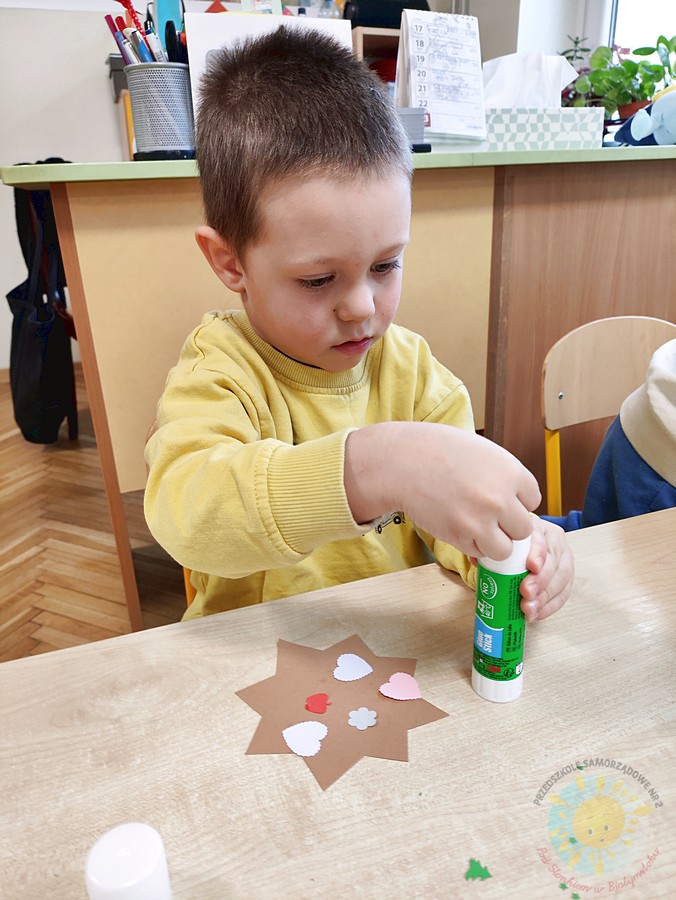 Siedzące dzieci przy stole i wykonują pracę plastyczną - Przedszkole Samorządowe Nr 2 Pod Słonkiem w Białymstoku