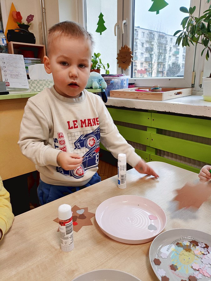 Siedzące dzieci przy stole i wykonują pracę plastyczną - Przedszkole Samorządowe Nr 2 Pod Słonkiem w Białymstoku