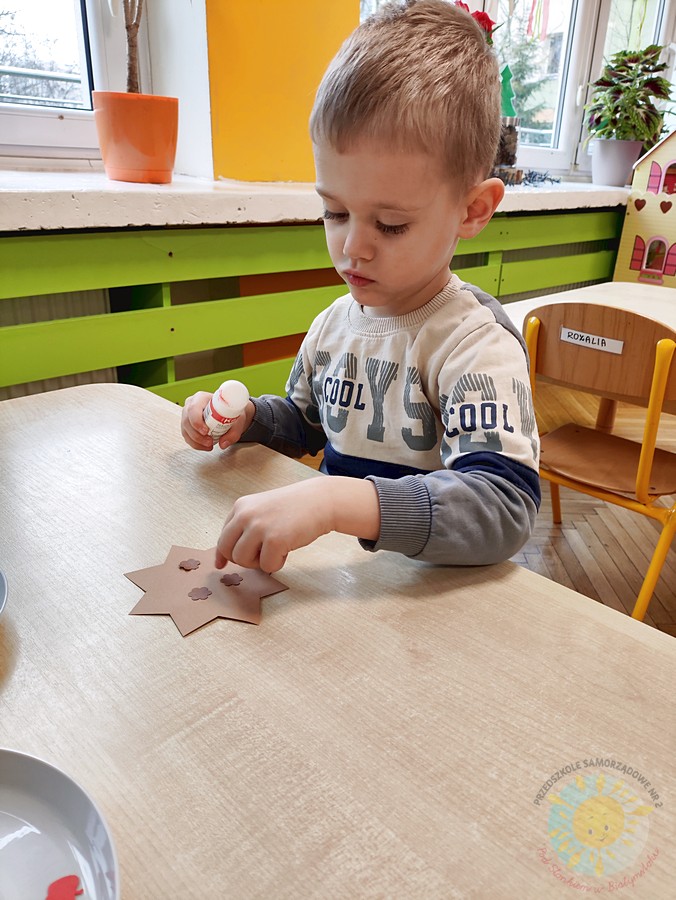 Siedzące dzieci przy stole i wykonują pracę plastyczną - Przedszkole Samorządowe Nr 2 Pod Słonkiem w Białymstoku