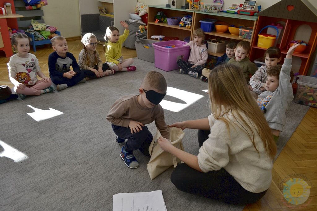 Siedzące dzieci na dywanie, które biorą udział w zajęciach - Przedszkole Samorządowe Nr 2 Pod Słonkiem w Białymstoku