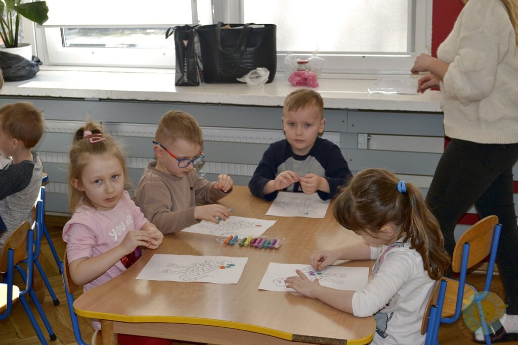 Siedzące dzieci przy przedszkolnym stoliku, wykonują pracę - Przedszkole Samorządowe Nr 2 Pod Słonkiem w Białymstoku