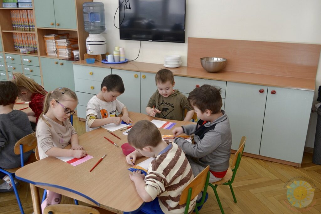 Siedzące dzieci przy przedszkolnym stoliku, wykonują pracę - Przedszkole Samorządowe Nr 2 Pod Słonkiem w Białymstoku