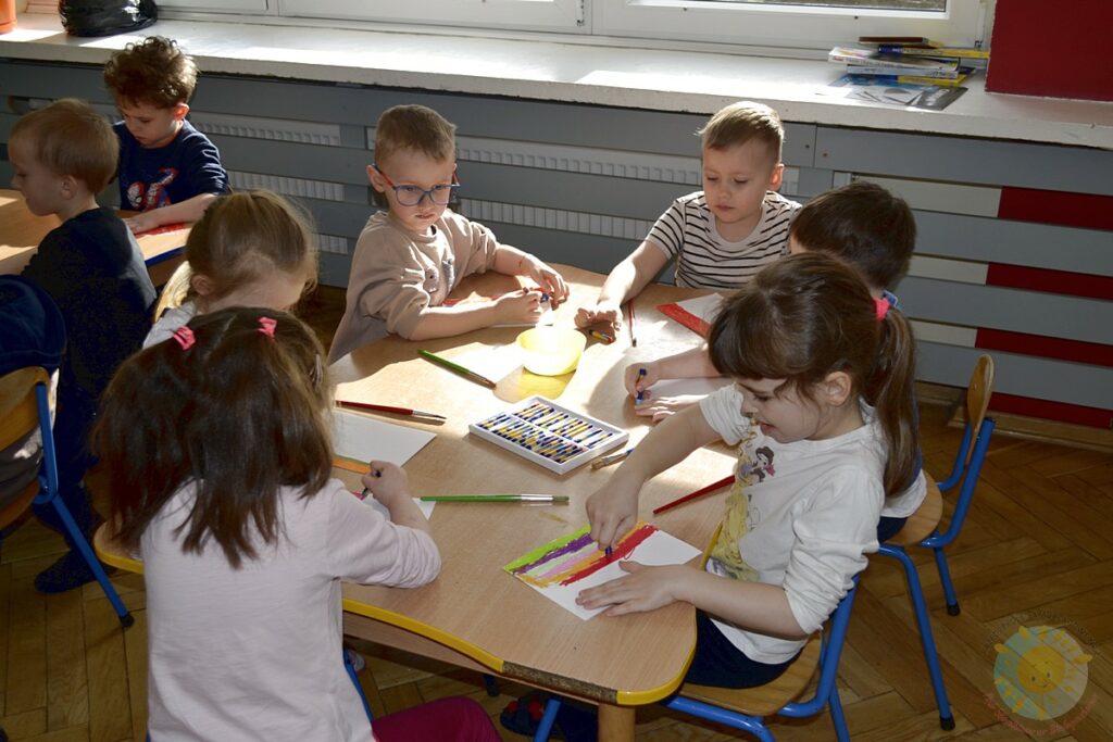 Siedzące dzieci przy przedszkolnym stoliku, wykonują pracę - Przedszkole Samorządowe Nr 2 Pod Słonkiem w Białymstoku