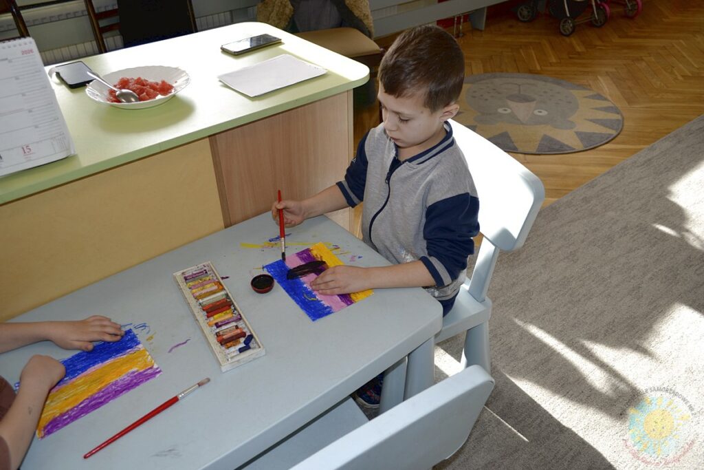 Siedzące dzieci przy przedszkolnym stoliku, wykonują pracę - Przedszkole Samorządowe Nr 2 Pod Słonkiem w Białymstoku