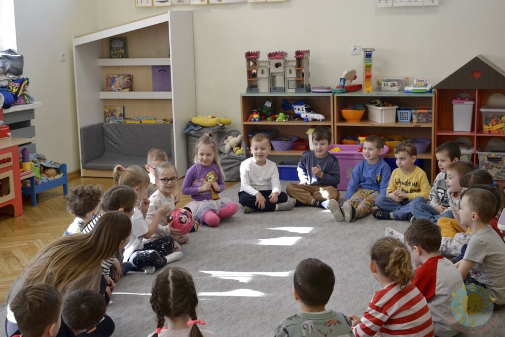 Siedzące dzieci na dywanie, które biorą udział w zajęciach - Przedszkole Samorządowe Nr 2 Pod Słonkiem w Białymstoku