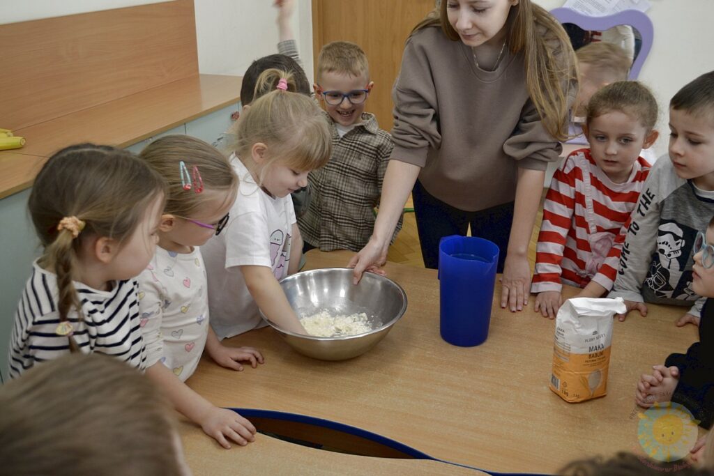 Siedzące dzieci przy przedszkolnym stoliku, wykonują pracę - Przedszkole Samorządowe Nr 2 Pod Słonkiem w Białymstoku