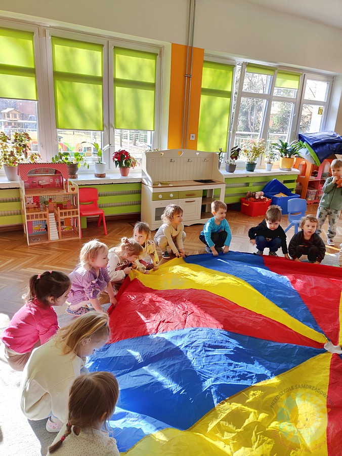Bawiące się dzieci chustą KLANZA na dywanie przedszkolnym - Przedszkole Samorządowe Nr 2 Pod Słonkiem w Białymstoku
