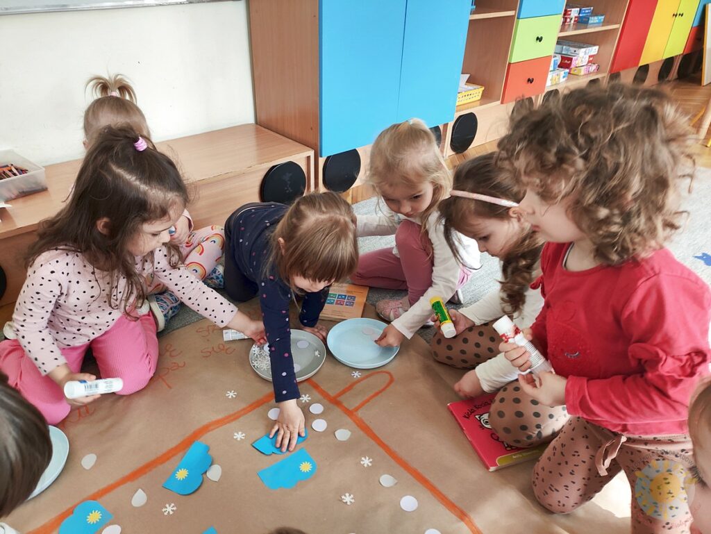 Siedzące dzieci na dywanie, które biorą udział w zajęciach - Przedszkole Samorządowe Nr 2 Pod Słonkiem w Białymstoku