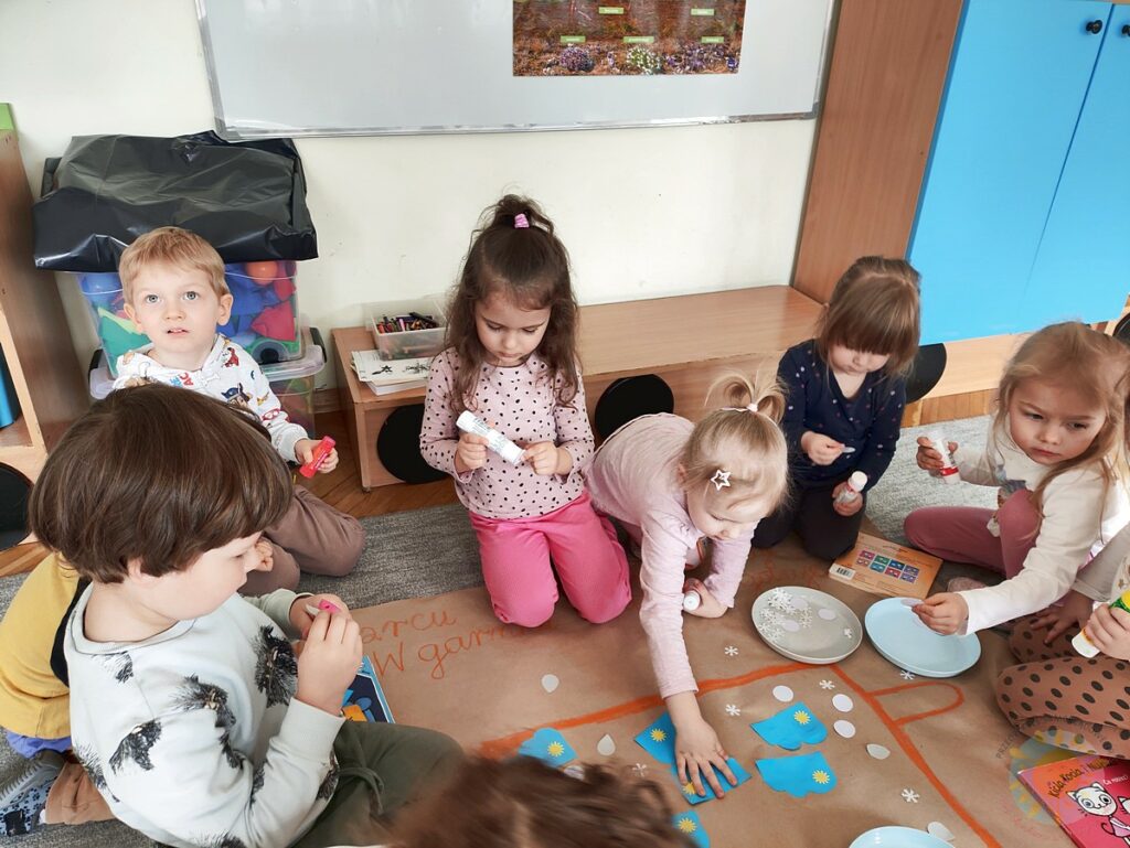 Siedzące dzieci na dywanie, które biorą udział w zajęciach - Przedszkole Samorządowe Nr 2 Pod Słonkiem w Białymstoku