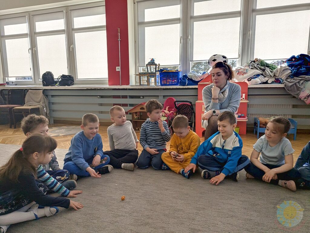 Siedzące dzieci na dywanie, które biorą udział w zajęciach - Przedszkole Samorządowe Nr 2 Pod Słonkiem w Białymstoku