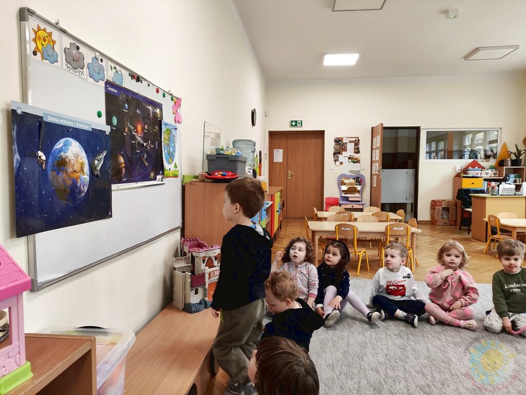 Siedzące dzieci na dywanie, które biorą udział w zajęciach - Przedszkole Samorządowe Nr 2 Pod Słonkiem w Białymstoku
