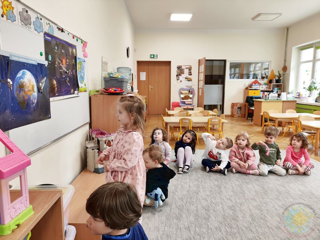 Siedzące dzieci na dywanie, które biorą udział w zajęciach - Przedszkole Samorządowe Nr 2 Pod Słonkiem w Białymstoku
