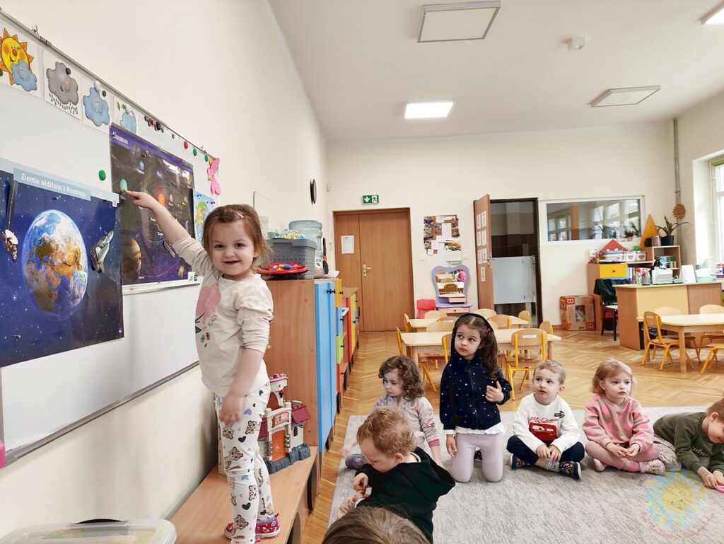 Siedzące dzieci na dywanie, które biorą udział w zajęciach - Przedszkole Samorządowe Nr 2 Pod Słonkiem w Białymstoku
