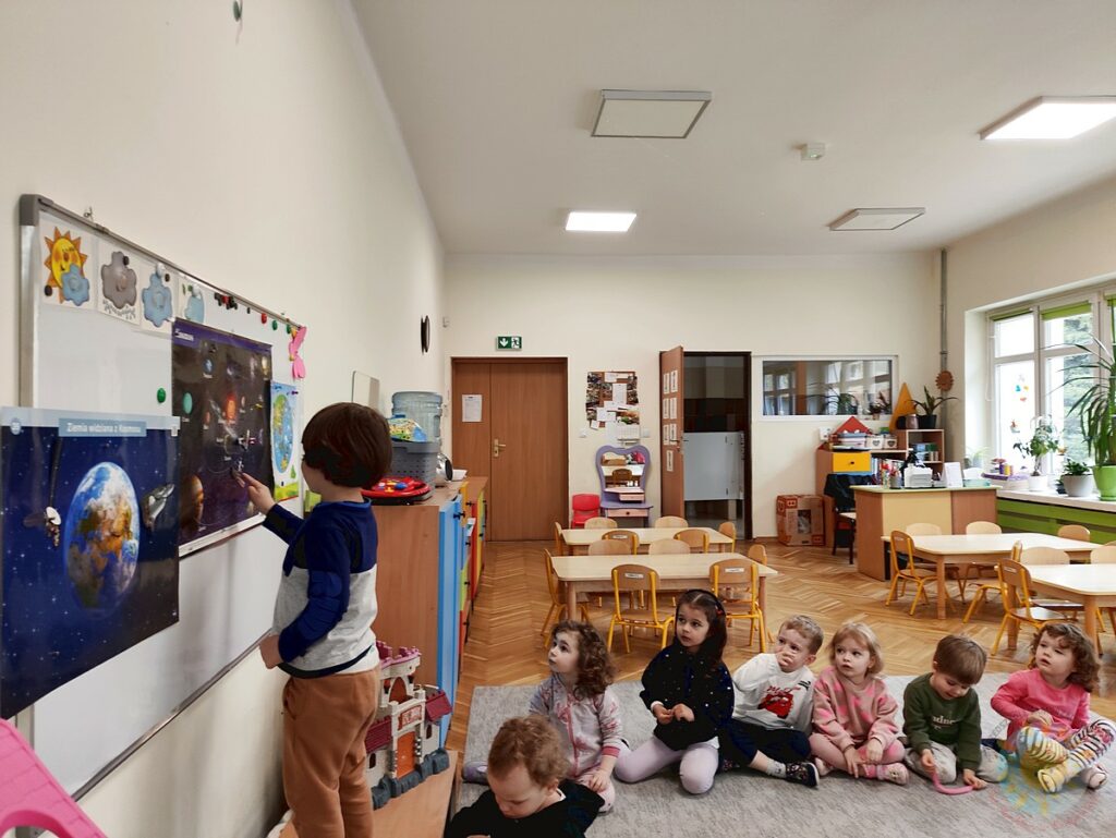 Siedzące dzieci na dywanie, które biorą udział w zajęciach - Przedszkole Samorządowe Nr 2 Pod Słonkiem w Białymstoku
