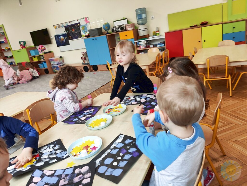 Siedzące dzieci przy stole i wykonują pracę plastyczną - Przedszkole Samorządowe Nr 2 Pod Słonkiem w Białymstoku