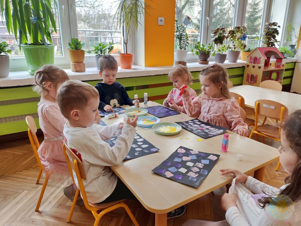 Siedzące dzieci przy stole i wykonują pracę plastyczną - Przedszkole Samorządowe Nr 2 Pod Słonkiem w Białymstoku